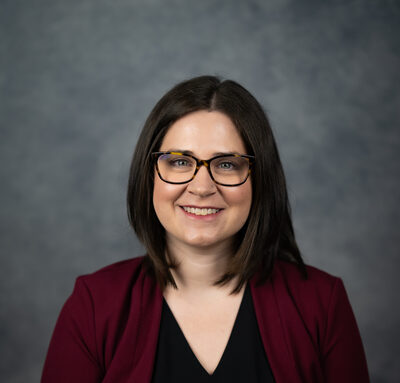 Michelle Rottschafer, a woman with dark hair and glasses, smiling in a maroon cardigan.